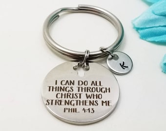 May include: Silver keychain with a round charm that reads "I can do all things through Christ who strengthens me Phil. 4:13". The keychain also has a smaller round charm with the letter "K" on it.