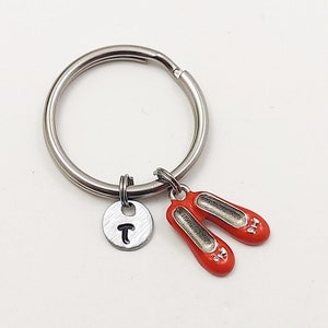 May include: A silver key chain with a red shoe charm and a silver charm with the letter "T" on it.