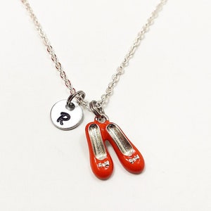May include: A silver necklace with a red shoe charm and a silver charm with the letter "R" on it.