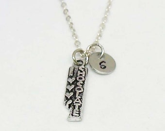 May include: A silver necklace with a charm that says "I love chocolate" and a small silver charm with the letter "G" on it.
