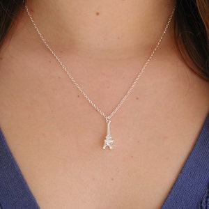 May include: A silver necklace with a small Eiffel Tower pendant.