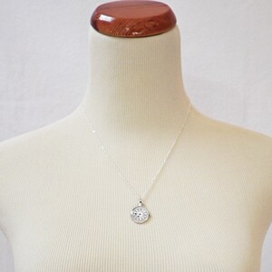 May include: A silver necklace with a round clock face pendant.
