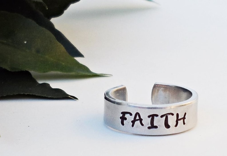 May include: A silver ring with the word "FAITH" engraved on it.