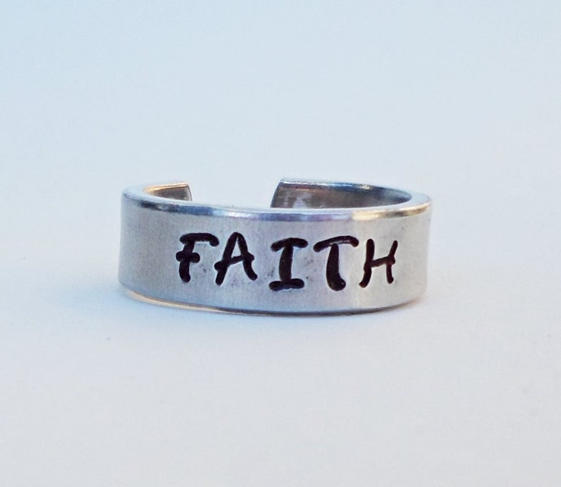 May include: A silver ring with the word "FAITH" engraved on it.
