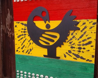 May include: A wooden wall art piece with a red, yellow, and green color scheme. A black silhouette of a bird is centered on the yellow section. Rows of white seashells are arranged along the top and bottom edges of the artwork.