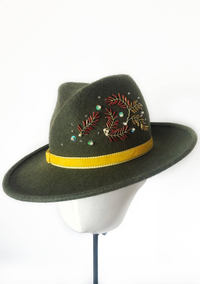 May include: A green felt fedora hat with a yellow ribbon and a beaded floral design.