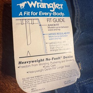 May include: A blue and white Wrangler brand tag with the text "A Fit for Every-Body" and a fit guide. The tag also states "Heavyweight No-Fault Denim" and "Freedom From Wrinkling, Puckering and Shrinking."