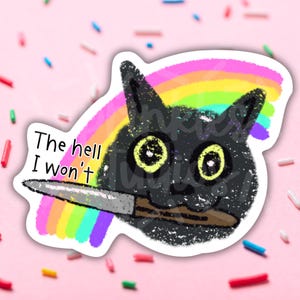 May include: A cartoon black cat with large yellow eyes is drawn with a rainbow behind it. The cat is holding a knife in its mouth and the text "The hell I won't" is written above the knife.