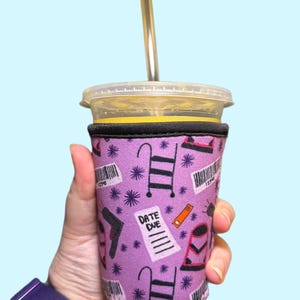 May include: Purple reusable cup sleeve with a pattern of ladders, stars, and the text "Date Due".