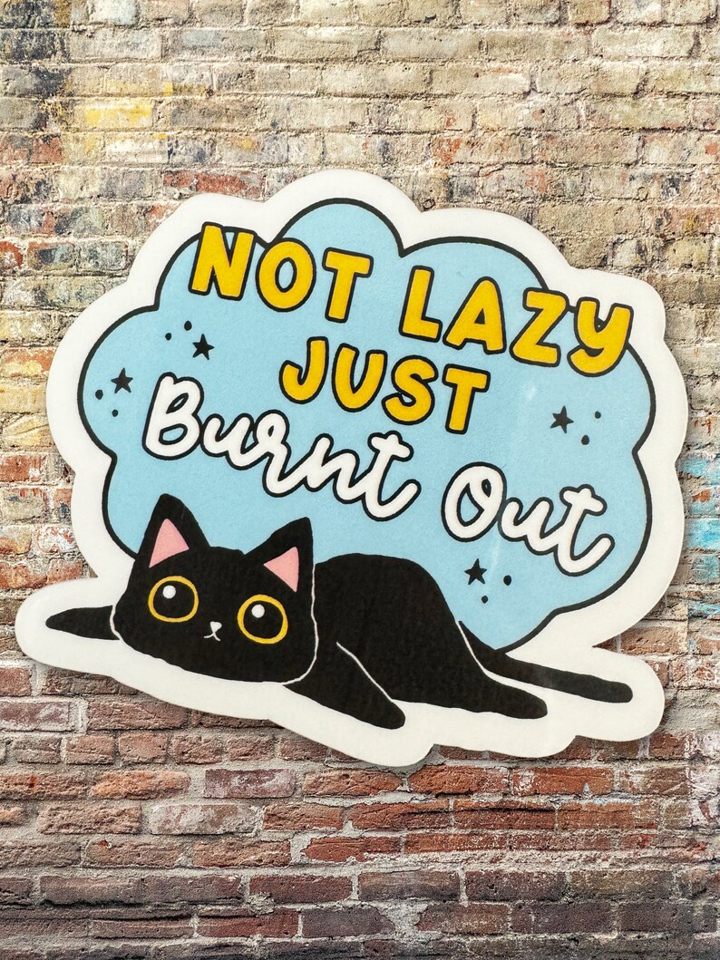 Może przedstawiać: Naklejka w kolorze niebieskim i białym z czarnym kotem i tekstem "Not Lazy Just Burnt Out" w ż&oacute;łtych literach.