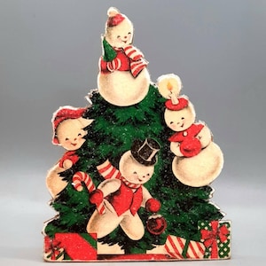 Puede incluir: Una tarjeta de Navidad vintage con cuatro mu&ntilde;ecos de nieve alrededor de un &aacute;rbol de Navidad verde. Los mu&ntilde;ecos de nieve llevan sombreros y bufandas rojas y blancas. El &aacute;rbol est&aacute; decorado con bastones de caramelo rojos y blancos y un lazo rojo. Los mu&ntilde;ecos de nieve sonr&iacute;en y sostienen regalos.