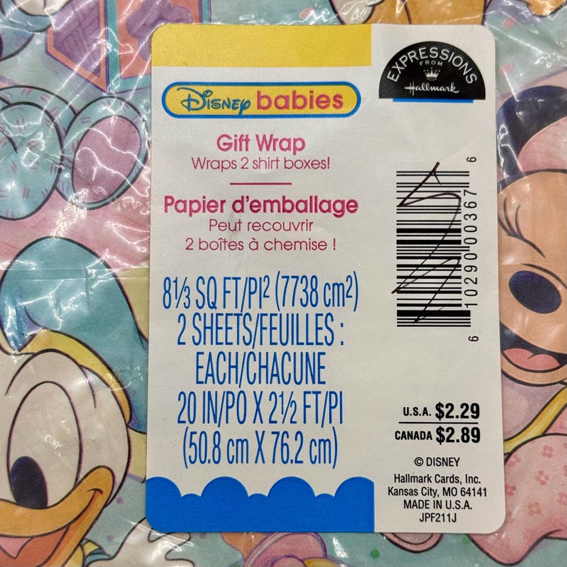 May include: Disney Babies gift wrap in a clear plastic package. The label includes the text "Gift Wrap" and "Papier d'emballage". The wrap is 50.8 cm x 76.2 cm and covers two shirt boxes. The package has a Disney and Hallmark logo.