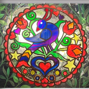 May include: A stained glass window featuring a colorful bird design. The bird is primarily blue and purple, surrounded by red tulips, green leaves, yellow stars, and hearts. The artwork is framed in a white window.