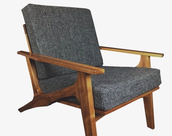 May include: A gray upholstered armchair with wooden legs and arms. The chair has a simple, mid-century modern design.