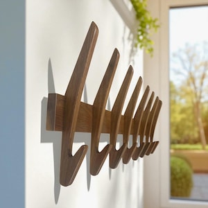 May include: A wooden wall-mounted coat rack with a series of angled hooks. The rack is made of dark brown wood and is mounted on a white wall. The hooks are evenly spaced and have a curved design.