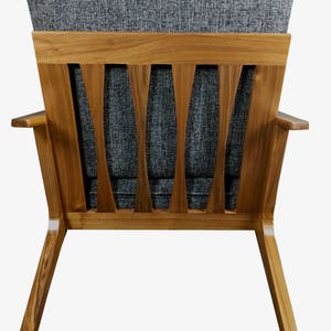 May include: A gray fabric armchair with a wooden frame and a slatted back. The chair has a mid-century modern design.