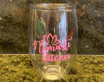May include: Clear glass wine glass with a pink vinyl decal that says "Namaste Bitches" with a pink lotus flower graphic.