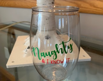 May include: Clear plastic wine glass with a green and red vinyl decal that says "Naughty & I Know It".