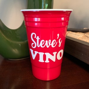 May include: Red plastic cup with white lettering that says "Steve's Vino".