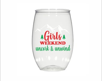 May include: Clear glass wine glass with a red and green design that says "Girls Weekend uncork & unwind".