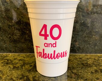 May include: White plastic cup with the text "40 and Fabulous" in pink lettering.