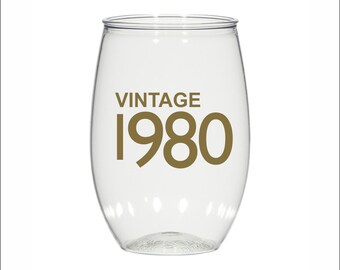 May include: Clear plastic wine glass with the text "Vintage 1980" printed in gold.