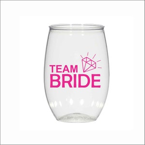 May include: Clear plastic wine glass with a pink diamond and the text "TEAM BRIDE" printed on the side.