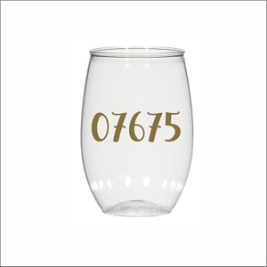 May include: Clear plastic wine glass with the number 07675 printed in gold on the side.