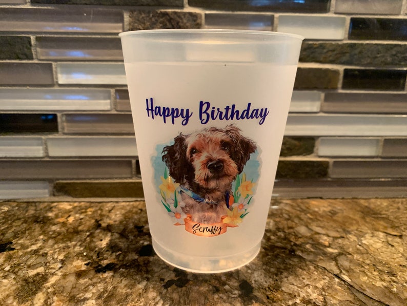 May include: White plastic cup with a personalized design featuring a brown and white dog with the text "Happy Birthday" and the name "Scruffy" in blue.