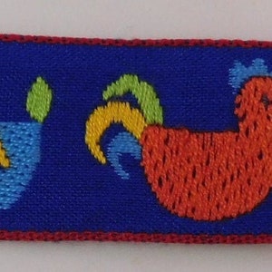 May include: A blue ribbon with a repeating pattern of embroidered roosters, flowers, and horses. The rooster is red, the flower is yellow, and the horse is blue. The ribbon has a red border.