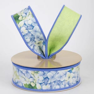 May include: A roll of decorative ribbon featuring a floral hydrangea pattern in shades of blue, white, and green. The ribbon has a light blue border and a bright green reverse side. Perfect for crafting and gift wrapping.