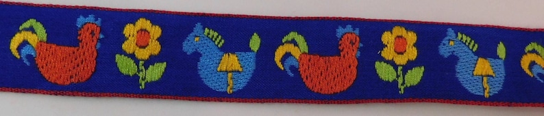 May include: A blue ribbon with a repeating pattern of embroidered roosters, flowers, and horses. The rooster is red, the flower is yellow, and the horse is blue. The ribbon has a red border.