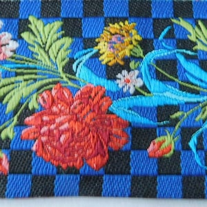 May include: A decorative ribbon featuring a blue and black checkered pattern. The ribbon is adorned with embroidered flowers in shades of red, pink, and yellow, along with green leaves and blue ribbons. This floral ribbon is suitable for various craft projects.