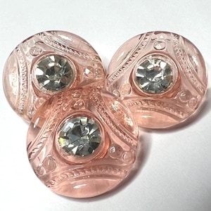 May include: A white ceramic mug with a black handle and the text "But First, Coffee" in a black, handwritten-style font. The mug is on a white surface.