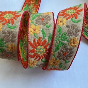 Cinta de tejido jacquard con diseño floral vintage, flores de edelweiss naranjas, amarillas, bronceadas y verdes sobre un fondo beige de ~1&quot;