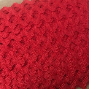 May include: Red wavy trim with a textured, woven design. This trim is perfect for adding a decorative touch to crafts, clothing, and home decor projects.