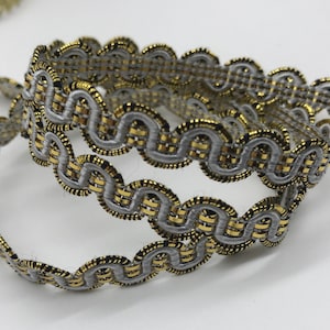 May include: Silver and gold trim with a wavy pattern. The trim is made of a woven fabric with a metallic thread.