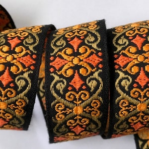 May include: Black woven ribbon with a repeating pattern of orange, gold, and black floral designs.