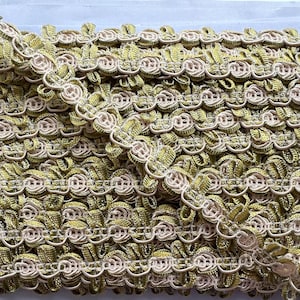 Puede incluir: Primer plano de un adorno decorativo con un diseño floral repetitivo. El adorno presenta una combinación de colores verde oliva y beige, creando una apariencia texturizada y detallada. Adecuado para diversos proyectos de artesanía y costura.