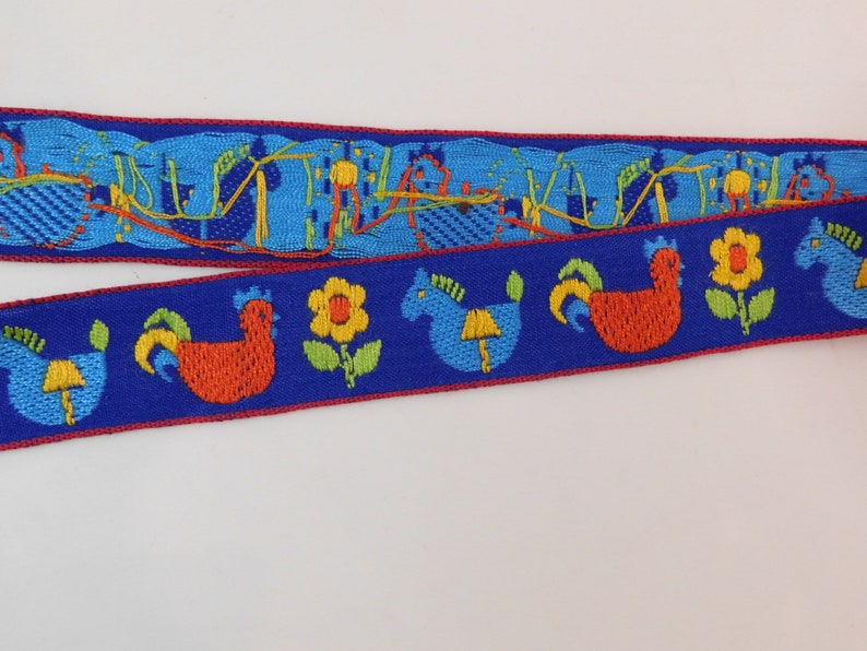 May include: Two strips of decorative ribbon with a blue background and a red border. One ribbon features a repeating pattern of blue and orange abstract shapes. The other ribbon has a pattern of rooster, horse, and flower designs.