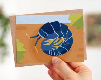 May include: A greeting card featuring a blue and yellow illustration of a pill bug curled up in a brown and green environment.