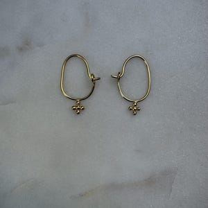 May include: A pair of gold hoop earrings with a small, textured cross charm hanging from each hoop.