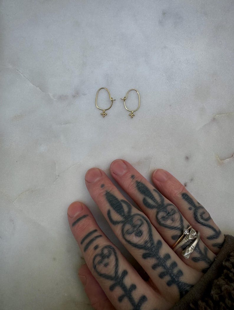 May include: A pair of gold hoop earrings with a small, textured charm hanging from each hoop.