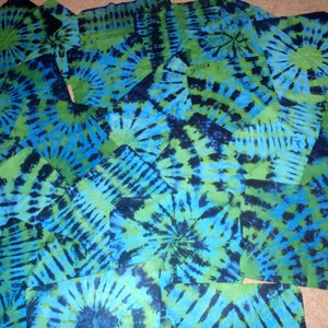 May include: A collection of blue and green tie-dye fabric squares. The fabric has a swirling pattern with shades of blue, green, and black.