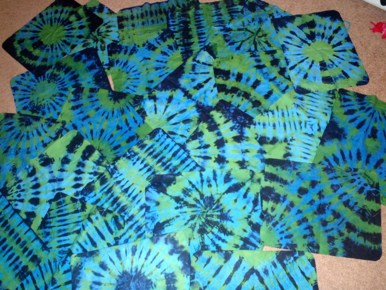 May include: A collection of blue and green tie-dye fabric squares. The fabric has a swirling pattern with shades of blue, green, and black.