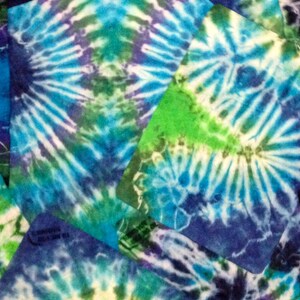 May include: A close-up of a tie-dye fabric with a swirling pattern of blue, green, and white. The fabric is made up of several pieces sewn together, creating a patchwork effect.