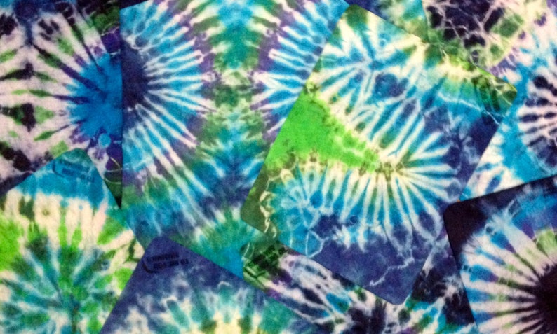 May include: A close-up of a tie-dye fabric with a swirling pattern of blue, green, and white. The fabric is made up of several pieces sewn together, creating a patchwork effect.