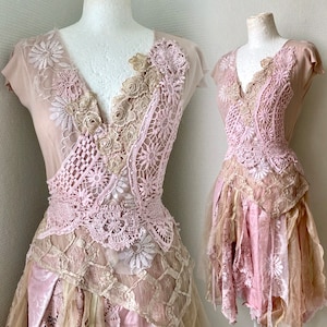 May include: A pink and beige dress with layers of lace and tulle. The dress has a V-neckline and short sleeves. The dress is decorated with floral lace appliques. The dress is made of a soft, flowing fabric. The dress is perfect for a special occasion.