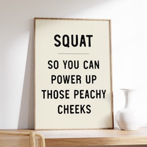 May include: A motivational quote poster with a beige background and black text that reads "SQUAT SO YOU CAN POWER UP THOSE PEACHY CHEEKS".