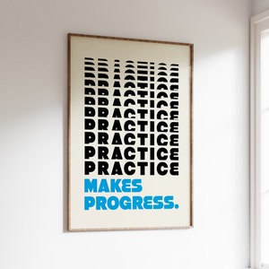 Op de afbeelding: Een ingelijste poster met het woord "PRACTICE" verticaal gestapeld in zwart, met de zin "MAKES PROGRESS." in blauw. De poster heeft een crèmekleurige achtergrond en een houten lijst, weergegeven tegen een witte muur.